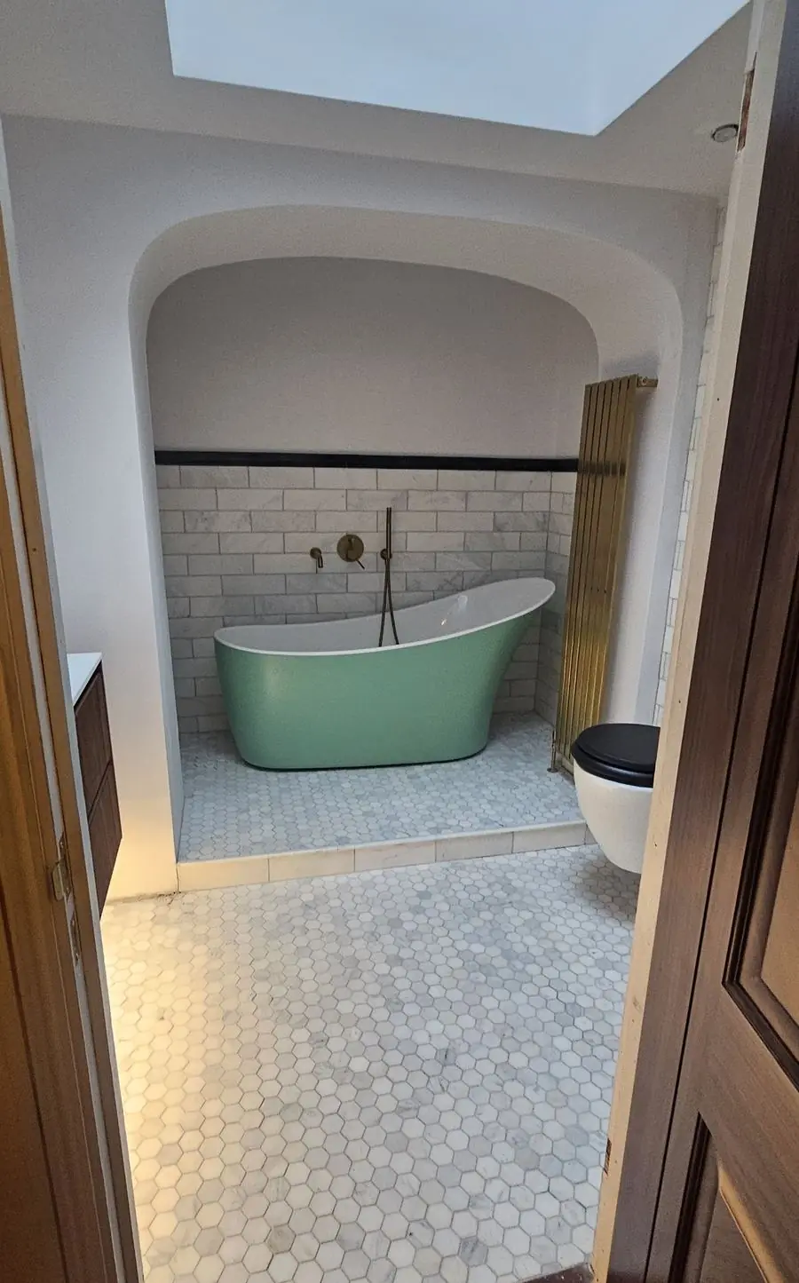 Renovated bathroom with an arched alcove, slipper bath and hexagon marble floor