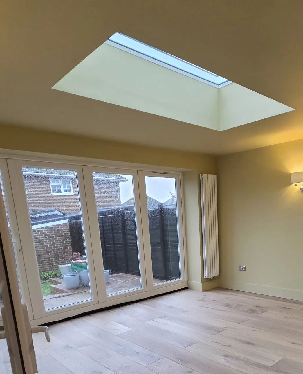 Finished rear extension with a roof light, white bifold doors to the garden, a vertical radiator and wide oak flooring