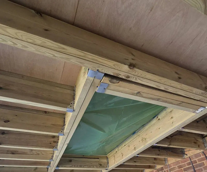 Extension roof under construction, with new joists framing the roof light opening and insulation boards on the walls