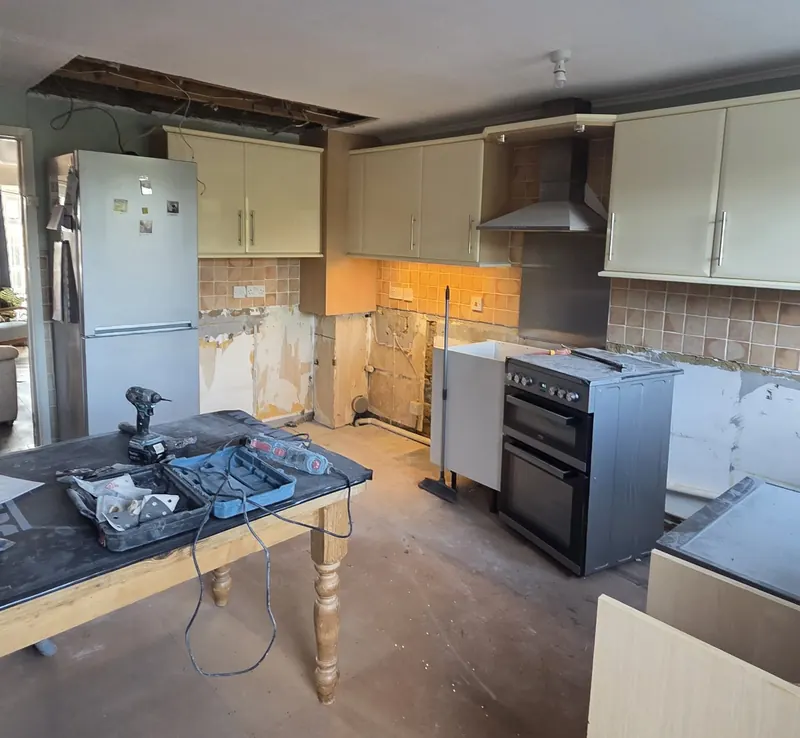 Old kitchen being stripped out, with tiles removed and the ceiling opened up