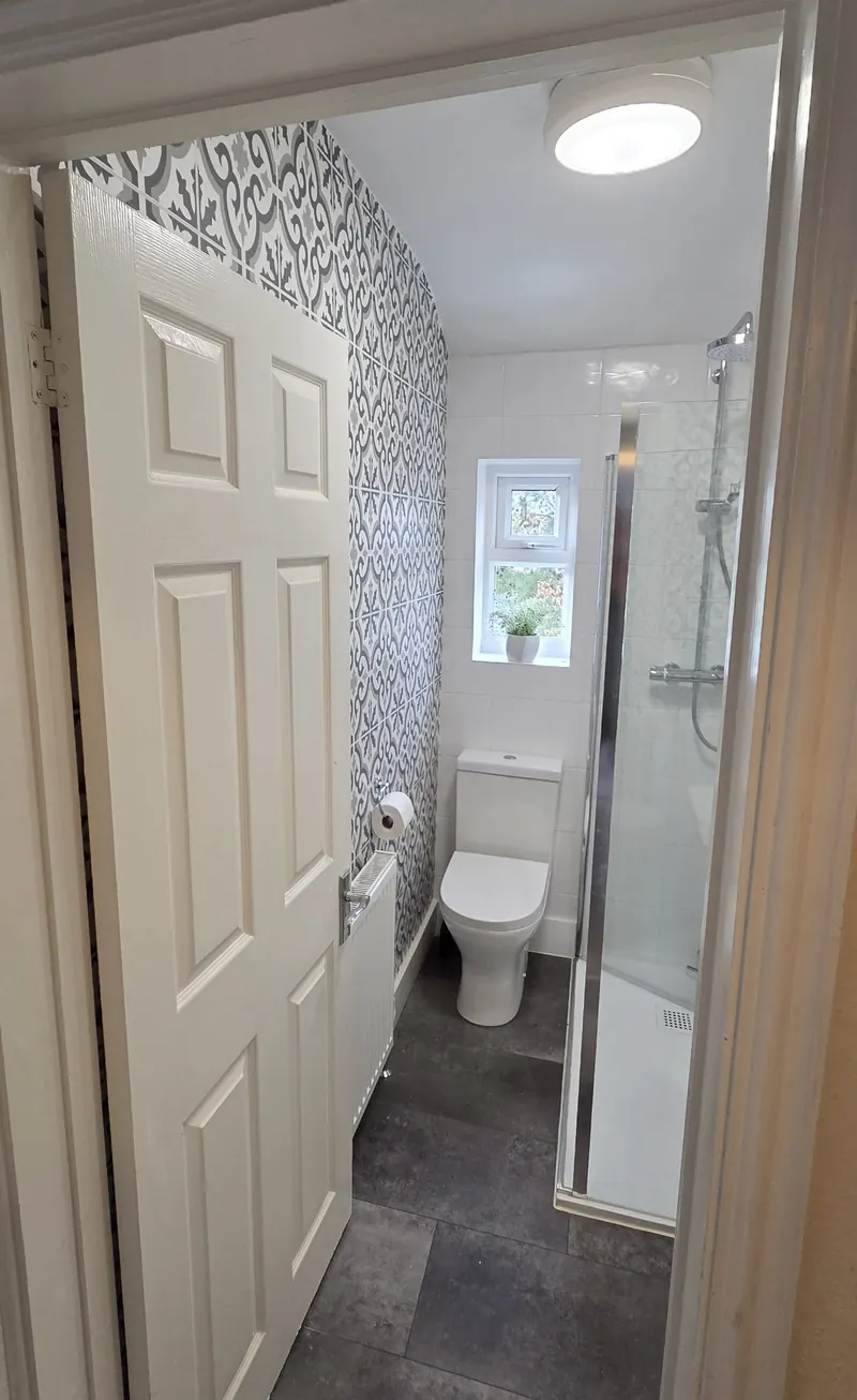 Doorway view of the small bathroom with a patterned feature tile wall