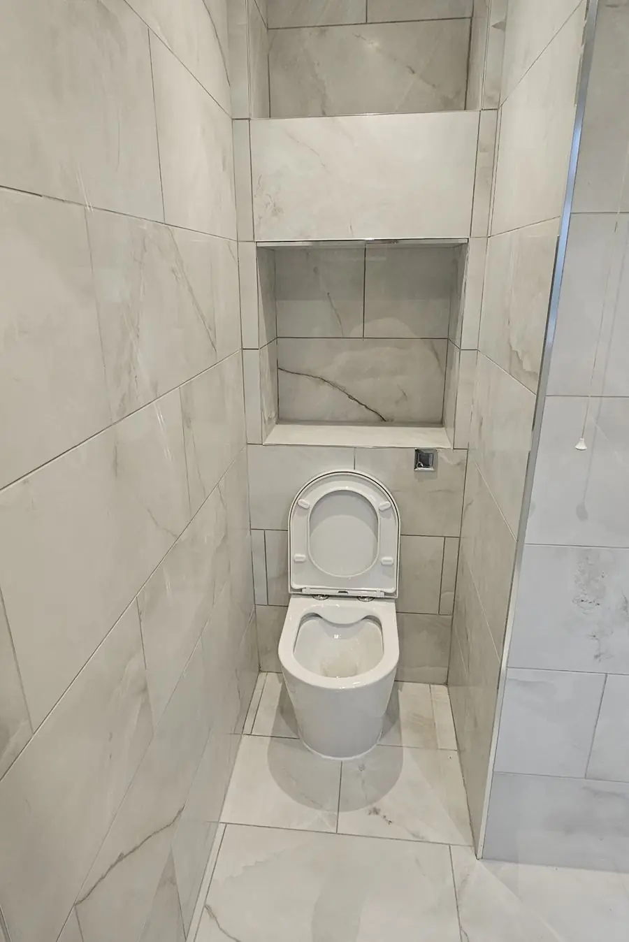Marble-effect tiled WC with a recessed niche and concealed cistern